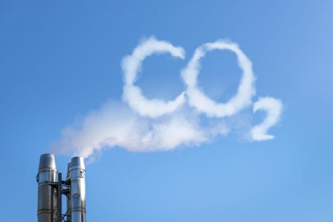 A cloud spelling CO2 wafts out of smoke stacks.