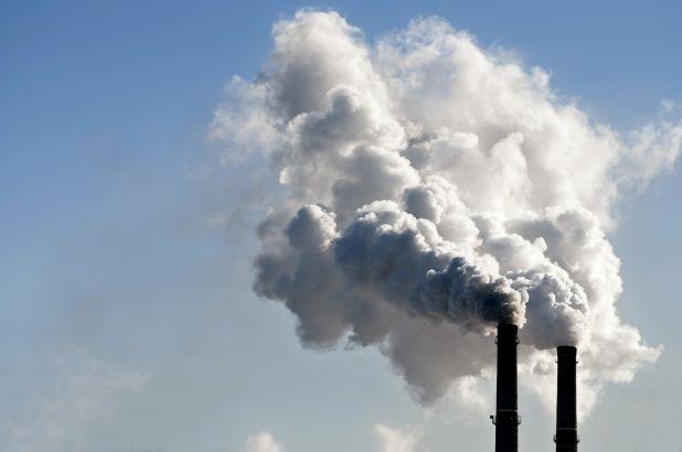 Two smokestacks releasing smoke into the air.