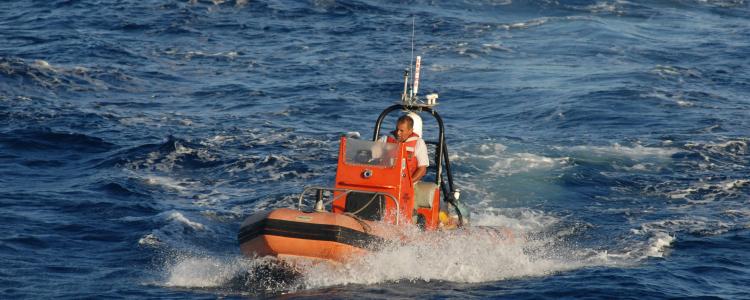 A small orange boat moving through the ocean
